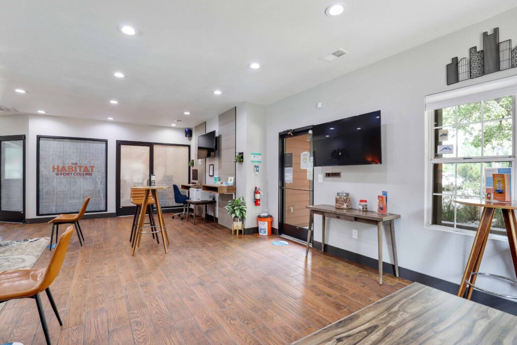 Clubhouse lobby area with large TVs and computer stations