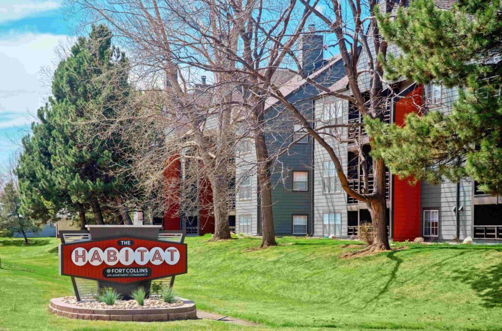 Exterior of habitat at fort collins with signage, large trees