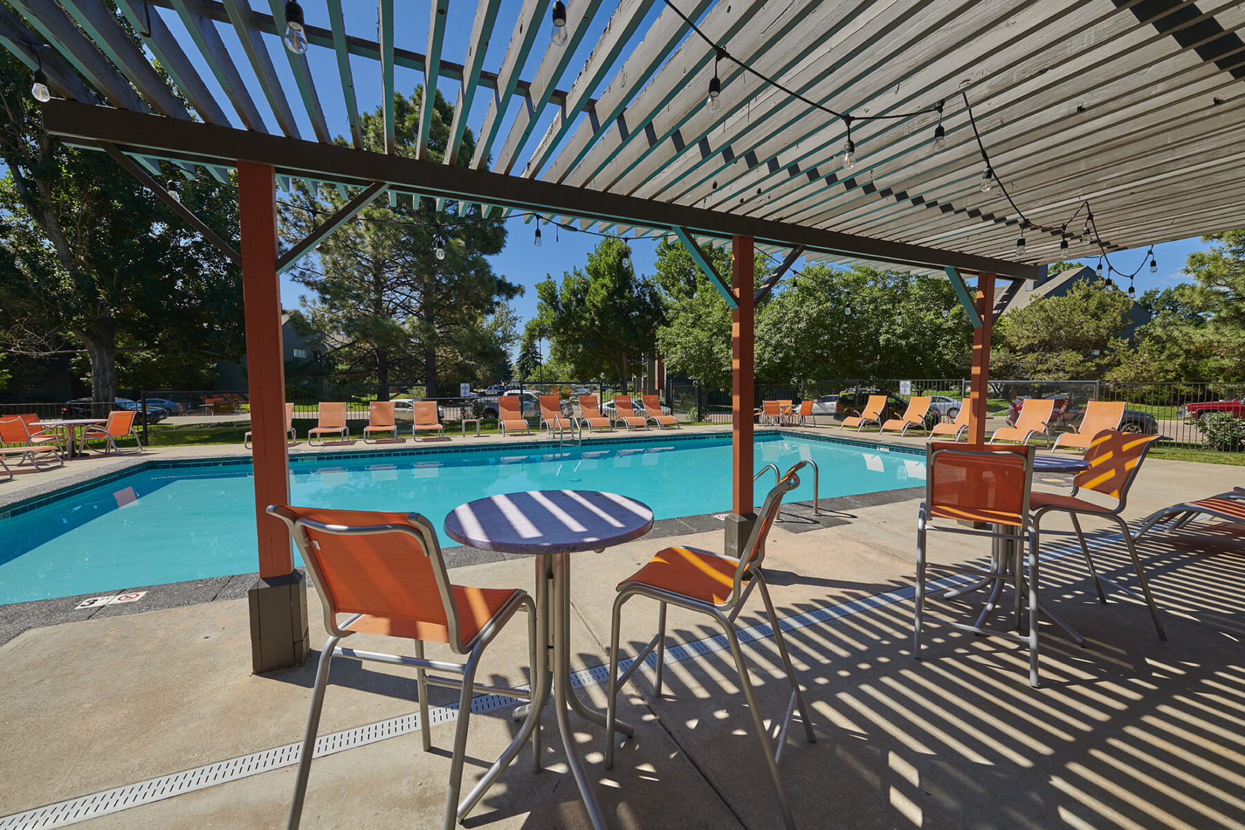 Swimming pool with deck seating and shaded tables